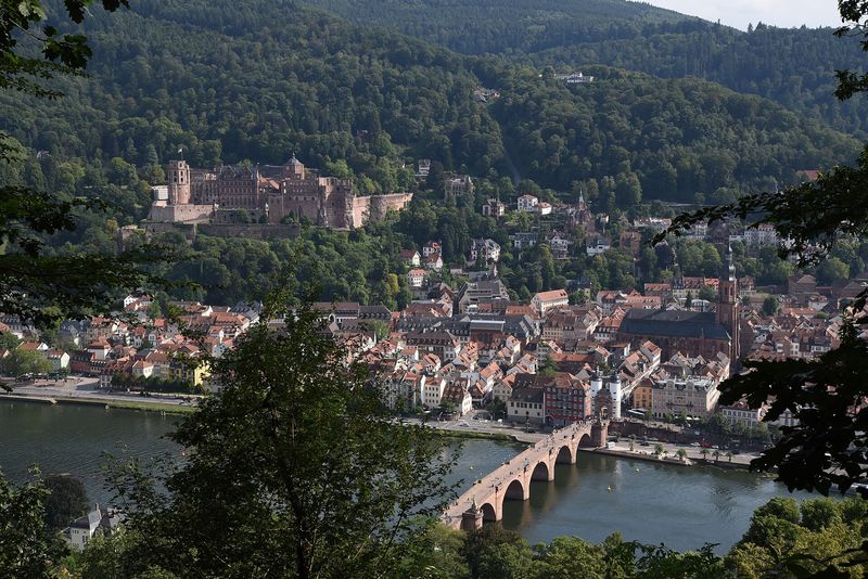 Blick über den Neckar auf die Alte Brücke, die Heidelberger Altstadt und die rote Sandsteinruine des Schlosses am Waldhang