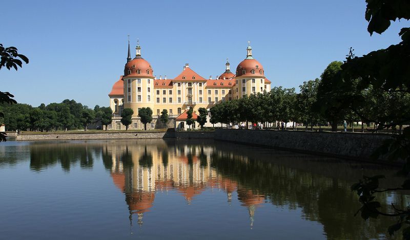Das barocke Jagdschloss Moritzburg mit roten Kuppeldächern, gespiegelt im Wasser des Schlossteichs