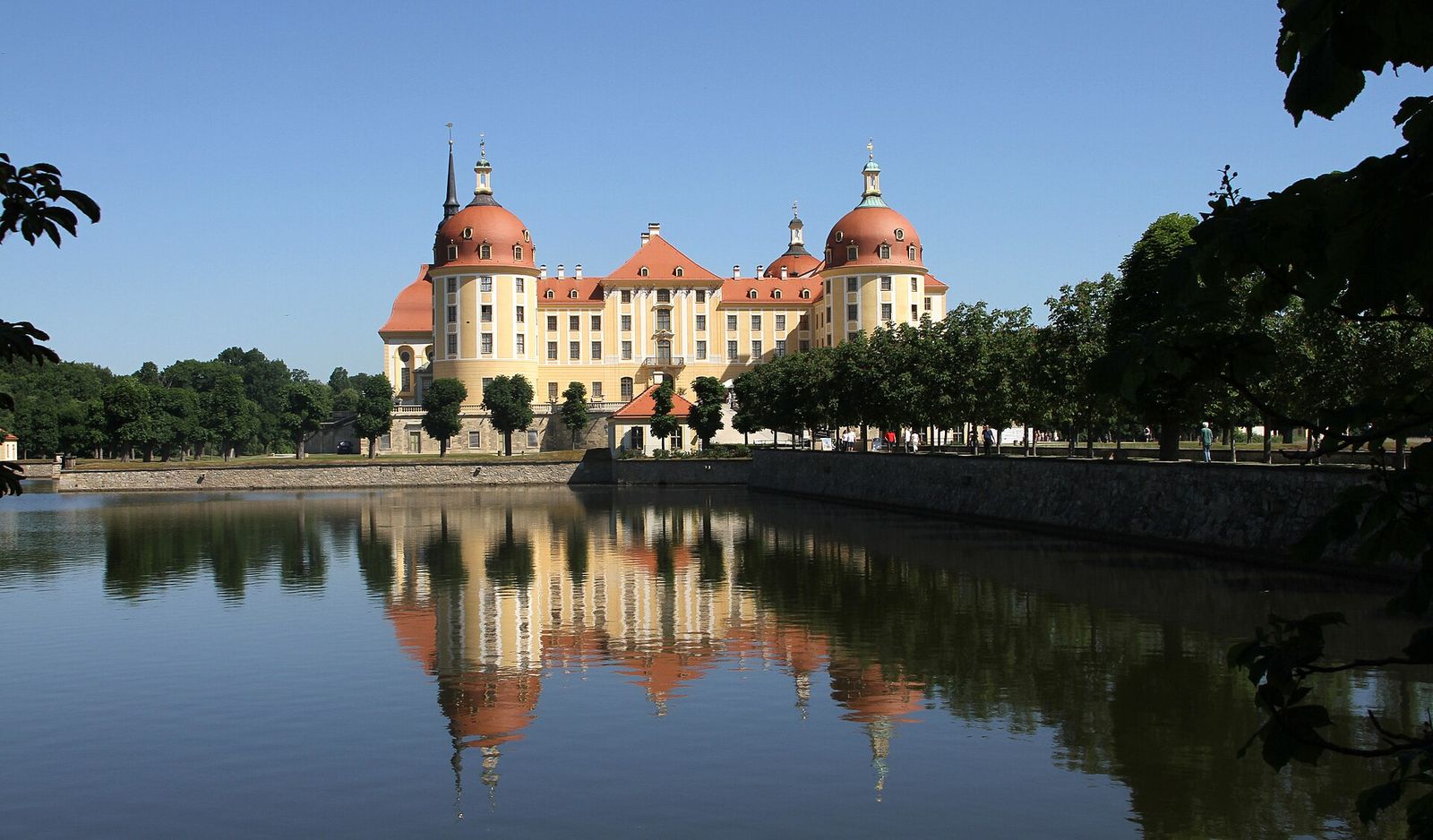 Das barocke Jagdschloss Moritzburg mit roten Kuppeldächern, gespiegelt im Wasser des Schlossteichs